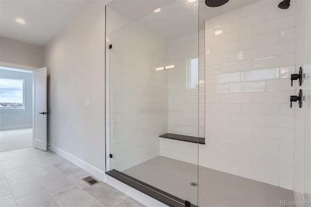 bathroom with tiled shower and tile patterned flooring