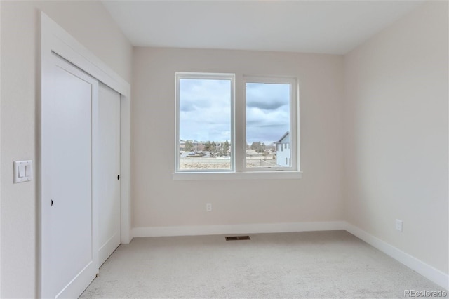 unfurnished bedroom featuring light colored carpet and a closet