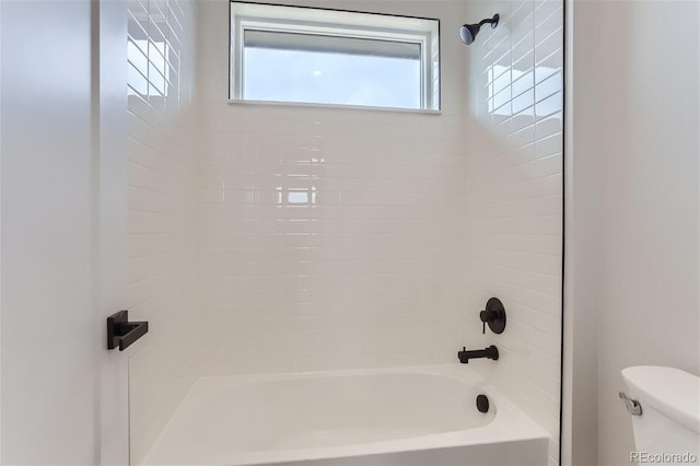 bathroom with tiled shower / bath combo and toilet