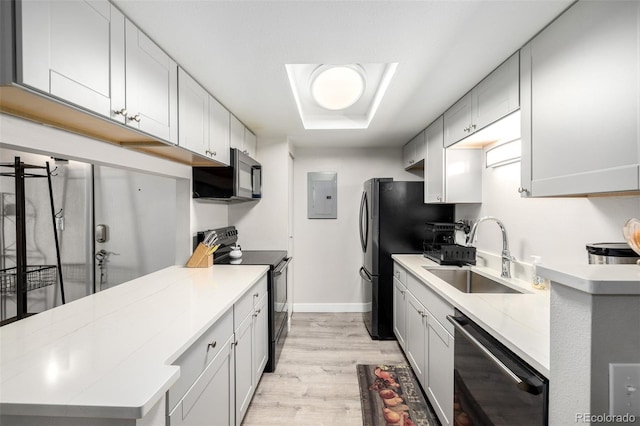 kitchen featuring black appliances, light wood-type flooring, electric panel, and sink