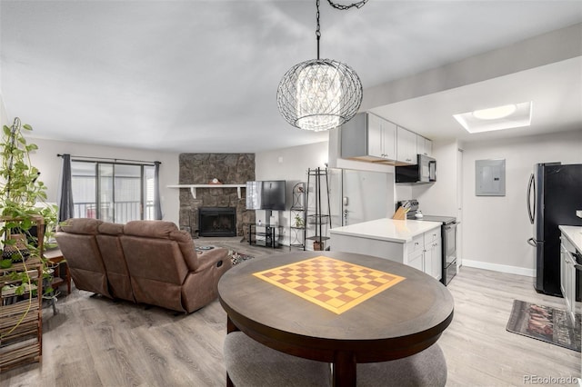 living room featuring a fireplace, light hardwood / wood-style floors, electric panel, and a notable chandelier