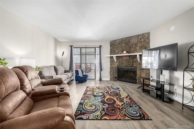 living room featuring wood-type flooring and a stone fireplace