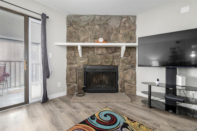 living room with hardwood / wood-style flooring, a stone fireplace, and plenty of natural light