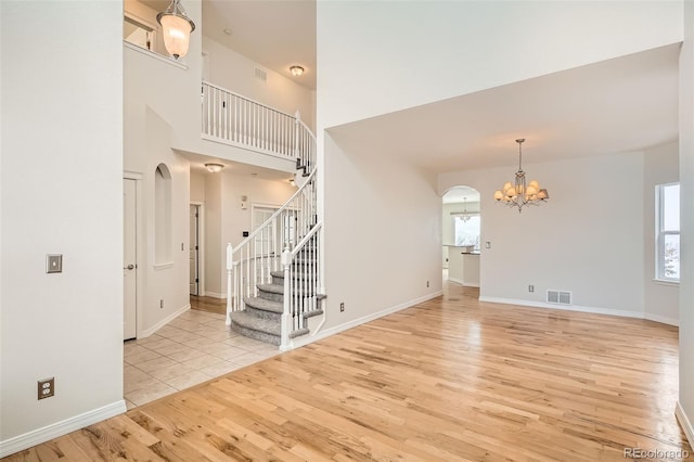 interior space with a towering ceiling, light wood-type flooring, and an inviting chandelier