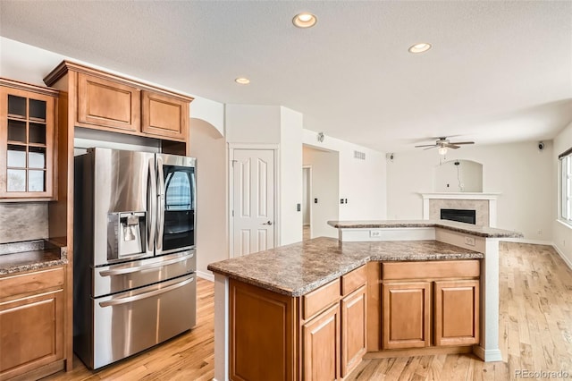 kitchen featuring ceiling fan, stainless steel fridge, a kitchen island, and light wood-type flooring