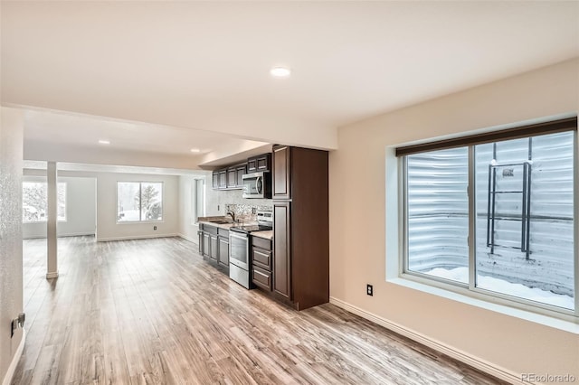 kitchen featuring decorative backsplash, appliances with stainless steel finishes, dark brown cabinets, sink, and light hardwood / wood-style floors