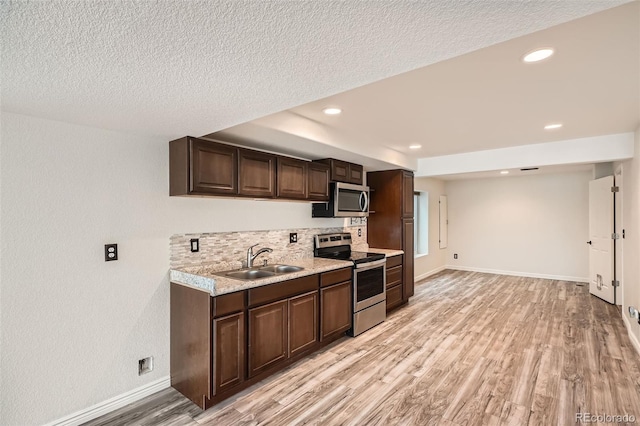 kitchen with dark brown cabinetry, sink, appliances with stainless steel finishes, and light hardwood / wood-style flooring