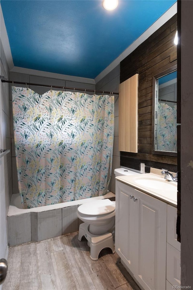 full bathroom featuring shower / tub combo with curtain, vanity, wood walls, and toilet