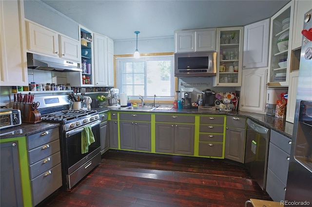 kitchen with appliances with stainless steel finishes, white cabinets, sink, pendant lighting, and dark hardwood / wood-style flooring