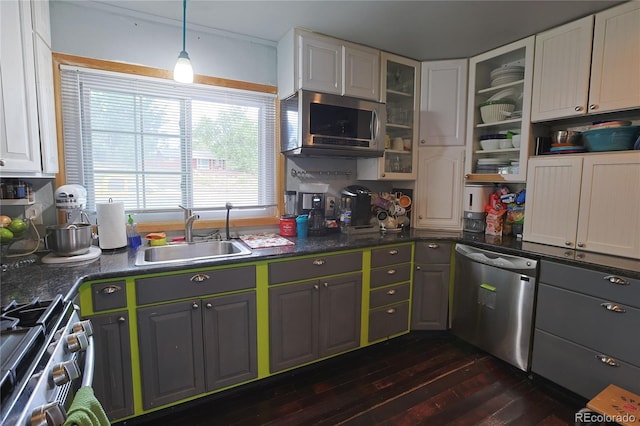 kitchen with appliances with stainless steel finishes, sink, pendant lighting, and white cabinets