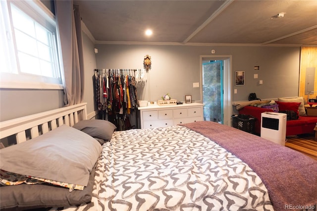 bedroom with wood-type flooring, ornamental molding, and electric panel