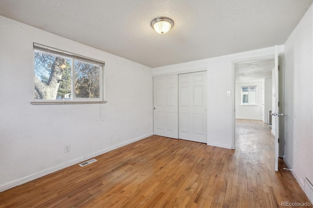 unfurnished bedroom featuring hardwood / wood-style floors, a textured ceiling, and a closet