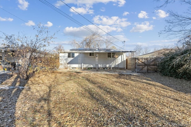 rear view of property with a lawn and solar panels