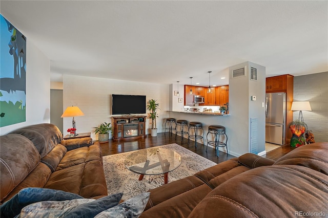 living area with dark wood-style floors, visible vents, and baseboards