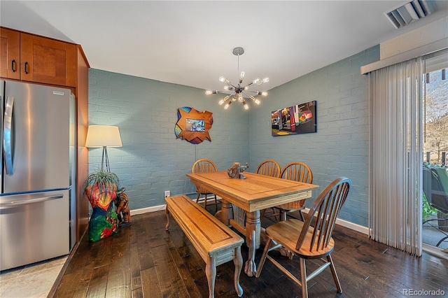 dining area featuring brick wall, visible vents, hardwood / wood-style floors, and an inviting chandelier