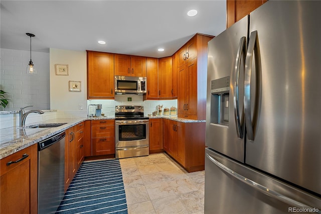 kitchen featuring decorative backsplash, brown cabinets, light stone countertops, stainless steel appliances, and a sink