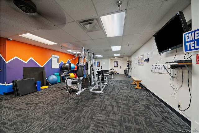 exercise room with a paneled ceiling, carpet flooring, visible vents, and baseboards