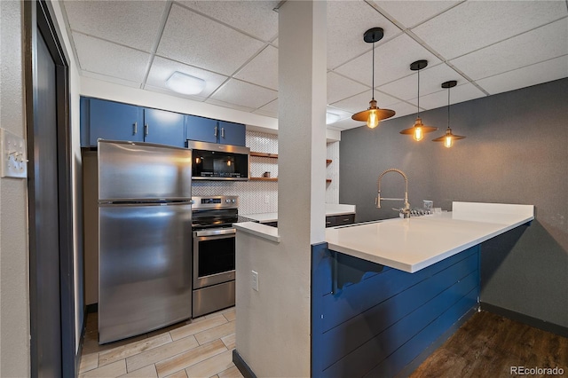 kitchen featuring a paneled ceiling, blue cabinetry, appliances with stainless steel finishes, and light wood finished floors