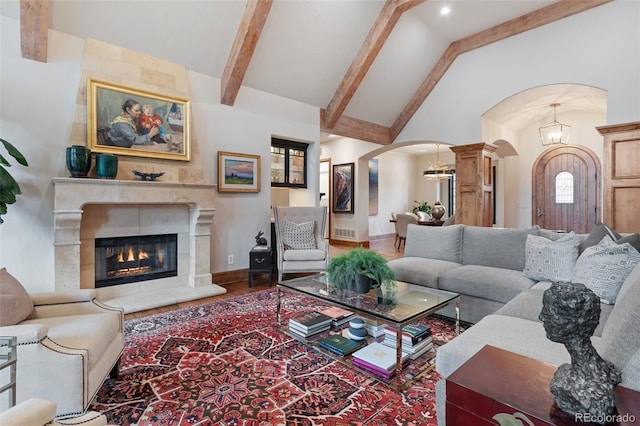 living room featuring wood finished floors, beam ceiling, a fireplace, high vaulted ceiling, and arched walkways