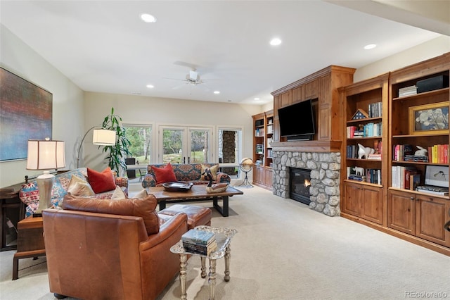 living area featuring a ceiling fan, recessed lighting, a stone fireplace, and light colored carpet
