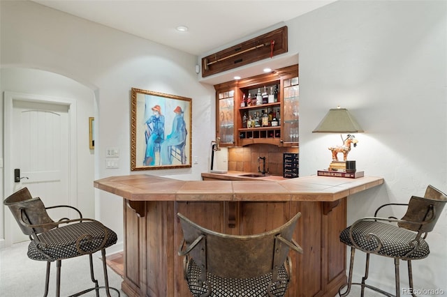 bar with baseboards, a sink, wet bar, and decorative backsplash