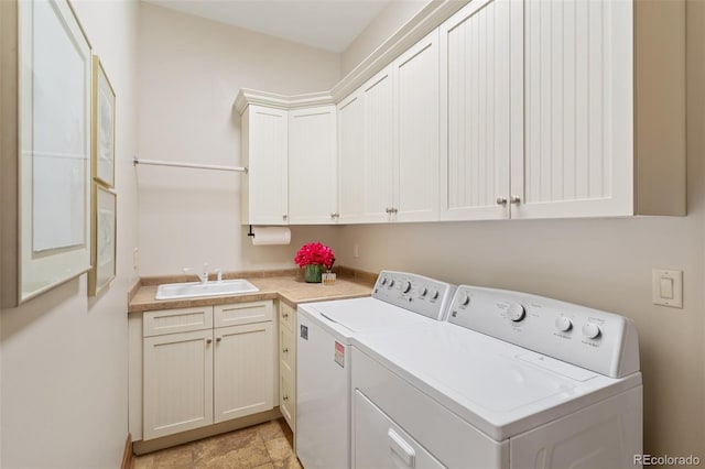 laundry area featuring a sink, stone finish floor, cabinet space, and washer and clothes dryer