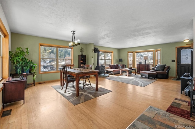 dining room featuring light hardwood / wood-style floors, an inviting chandelier, and a textured ceiling