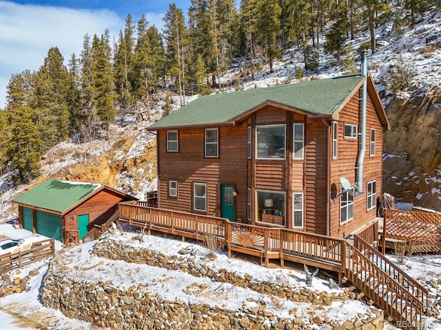 log cabin with a wooden deck, a garage, and an outbuilding