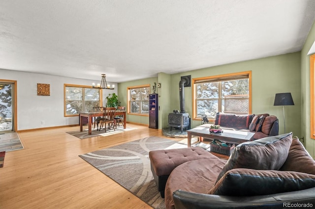 2476 S Beaver Creek Rd, Black Hawk, CO 80422 - living area with a wood stove, light wood-type flooring, a chandelier, baseboards, and a textured ceiling