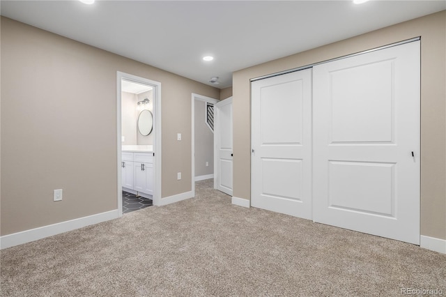 unfurnished bedroom featuring ensuite bath, a closet, and carpet floors