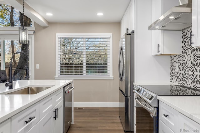 kitchen with stainless steel appliances, white cabinetry, wall chimney exhaust hood, and sink