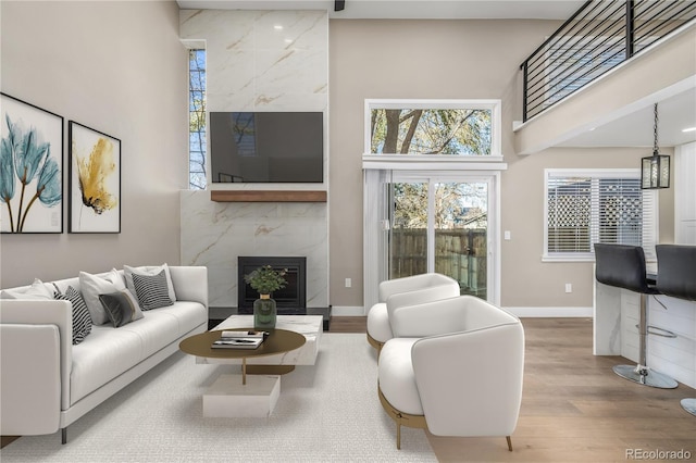 living room featuring hardwood / wood-style flooring, a premium fireplace, and a towering ceiling