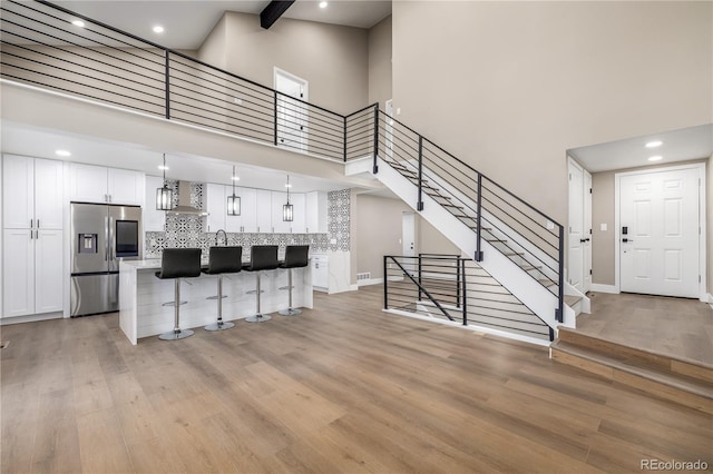 living room featuring light hardwood / wood-style floors, a towering ceiling, and beam ceiling