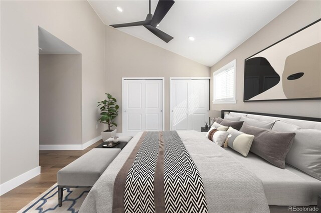 bedroom featuring wood-type flooring, vaulted ceiling, ceiling fan, and multiple closets