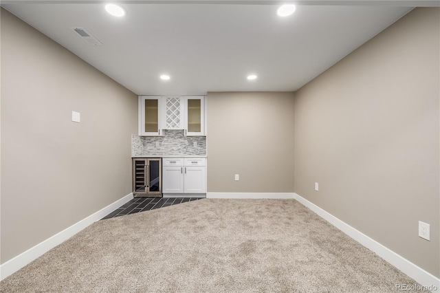 bar featuring dark colored carpet, decorative backsplash, white cabinetry, and beverage cooler