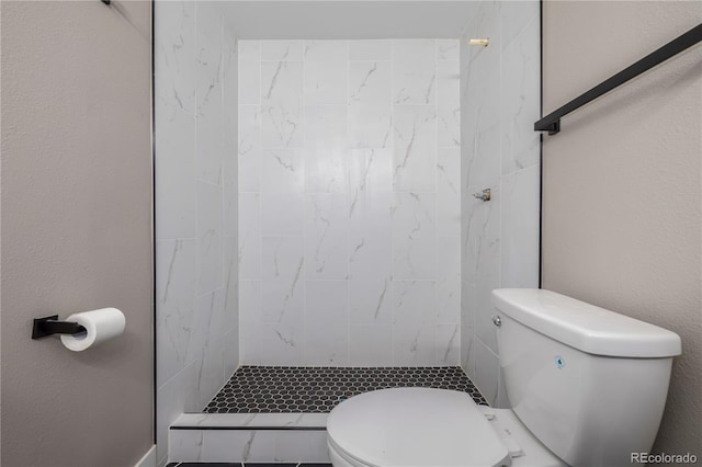 bathroom featuring tiled shower and toilet