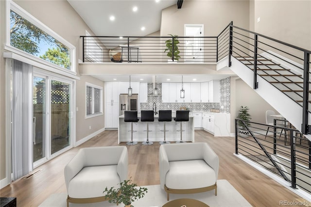 living room featuring a towering ceiling and light hardwood / wood-style flooring