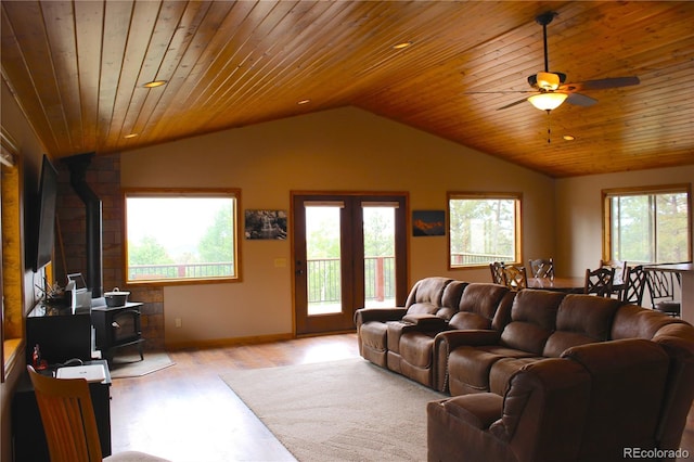 living room with vaulted ceiling, a wood stove, wood ceiling, and light wood-type flooring