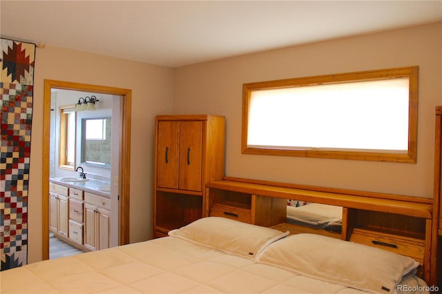 bedroom featuring light hardwood / wood-style floors, ensuite bathroom, and sink