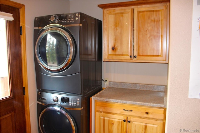 laundry area with stacked washing maching and dryer and cabinets