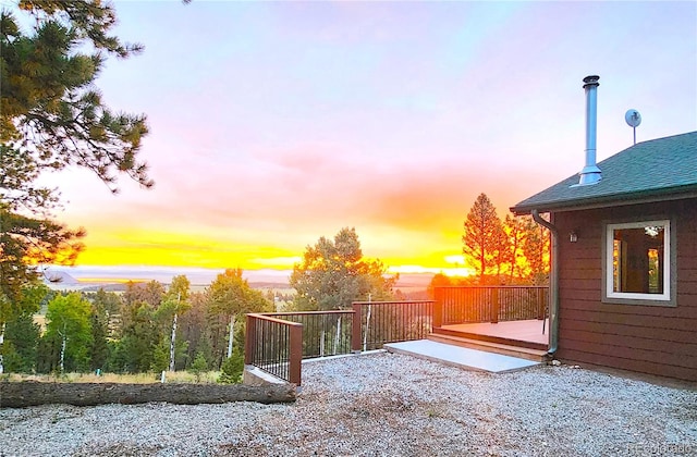 yard at dusk featuring a wooden deck