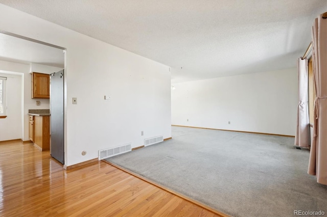 unfurnished room with light hardwood / wood-style floors and a textured ceiling