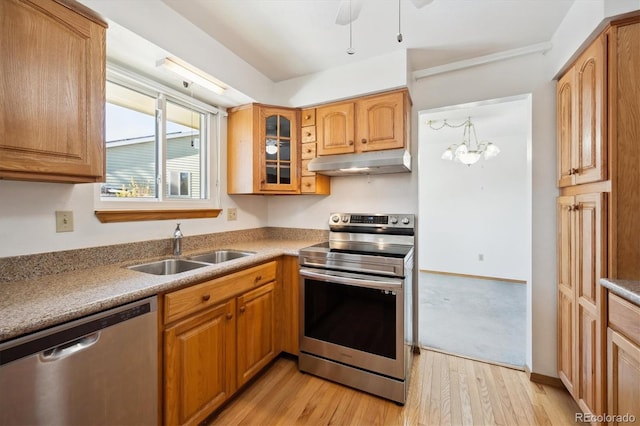 kitchen with stainless steel appliances, a notable chandelier, light hardwood / wood-style floors, and sink