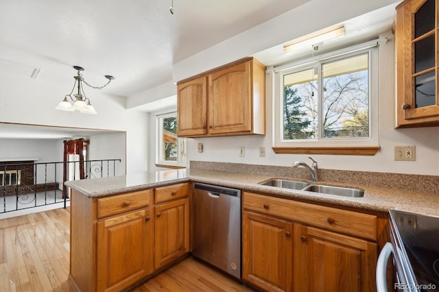 kitchen featuring kitchen peninsula, light wood-type flooring, sink, decorative light fixtures, and dishwasher