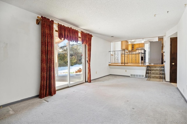 unfurnished living room with light colored carpet and a textured ceiling