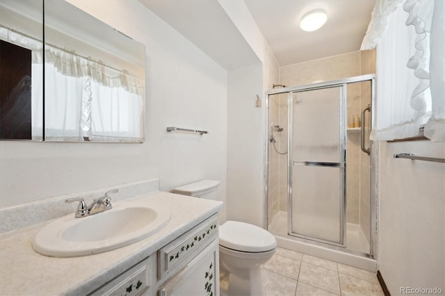 bathroom with tile patterned flooring, vanity, toilet, and a shower with shower door