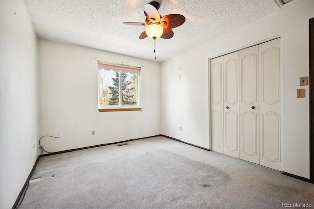 unfurnished bedroom featuring ceiling fan, a closet, light colored carpet, and a textured ceiling