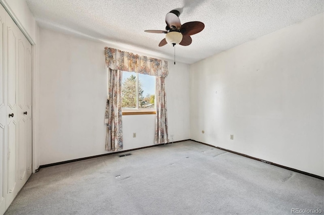 unfurnished bedroom with ceiling fan, a closet, light carpet, and a textured ceiling