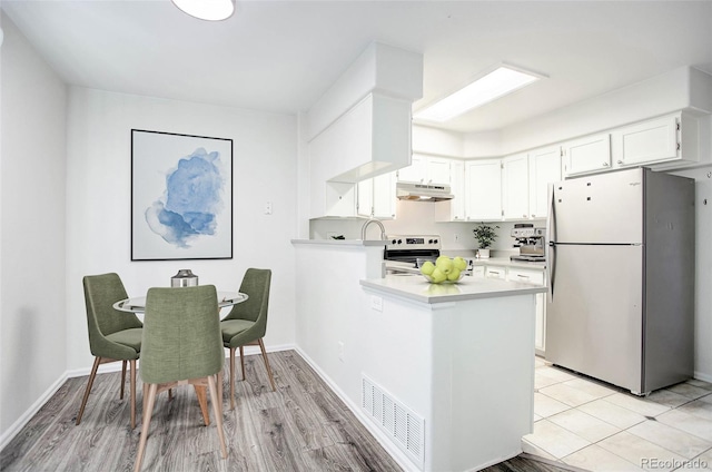 kitchen featuring range, white cabinets, light wood-type flooring, kitchen peninsula, and stainless steel refrigerator