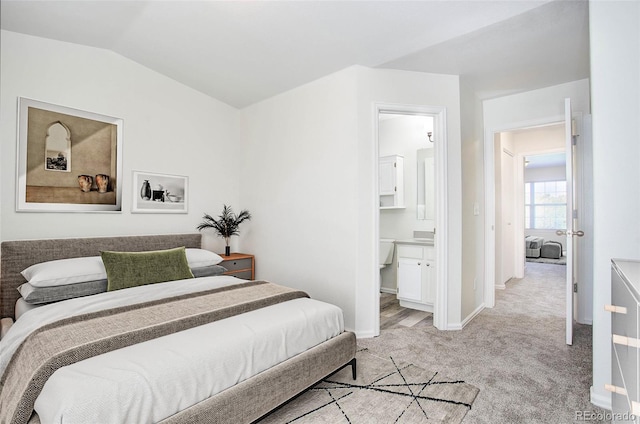 carpeted bedroom featuring connected bathroom and vaulted ceiling